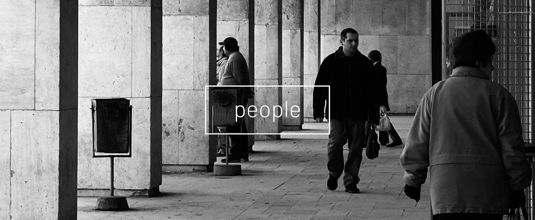 black and white photo of people walking in a train station building