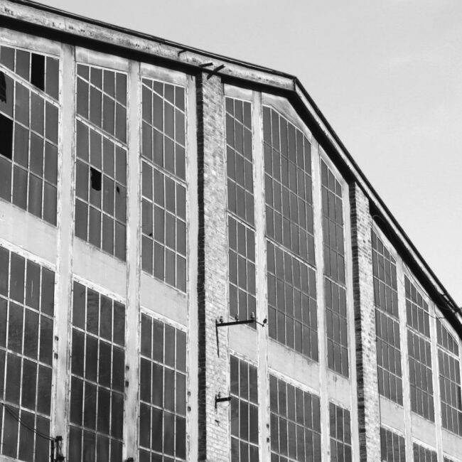 Black and white photo about an abandoned big building with rust